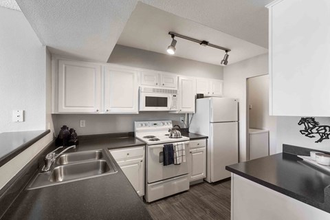 a kitchen with white appliances and black counter tops