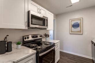 an apartment kitchen with stainless steel appliances and white cabinets