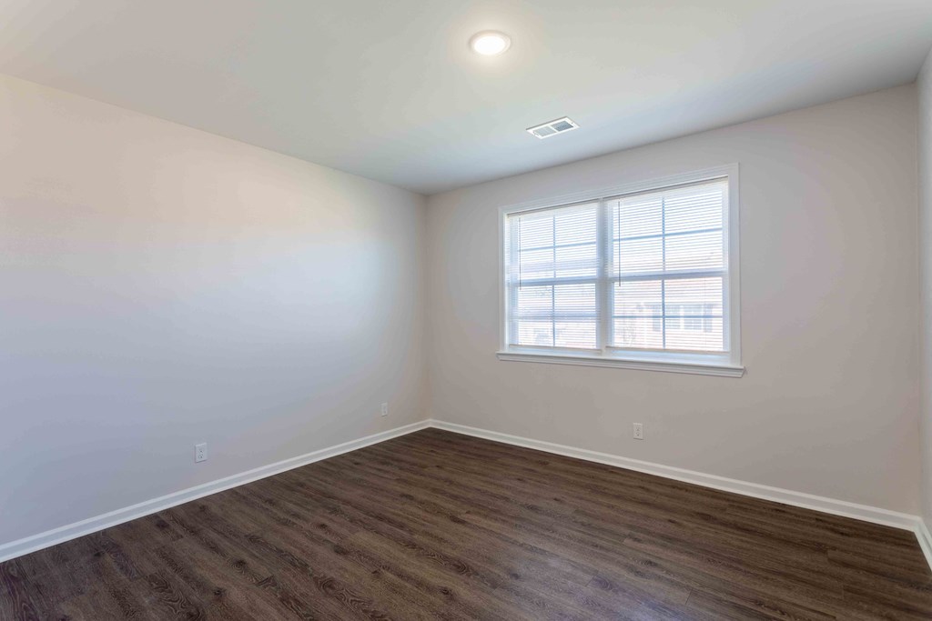 a bedroom with white walls and a window and wooden floors