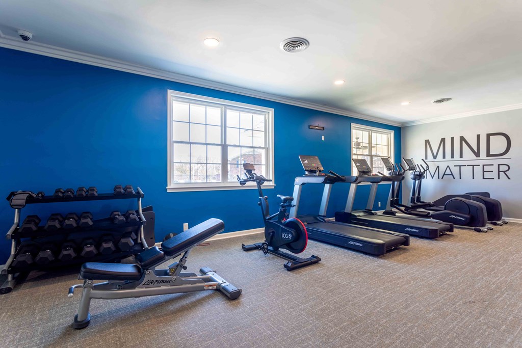 a gym with cardio equipment and weights in a room with a window