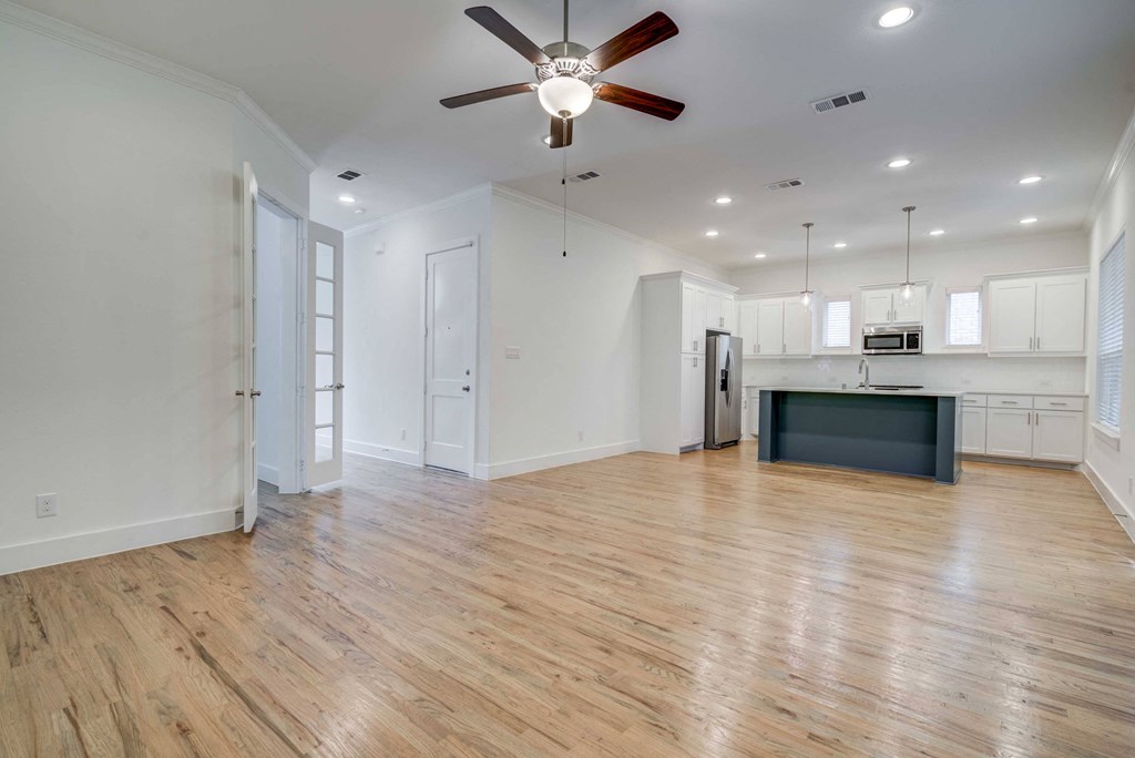 Allen TX Homes for Rent- Ridgeview Villas Apartments - Open-Concept Modern Living Room Adjacent To The Kitchen Featuring Light Brown Wood Flooring, Double Doors Leading To A Second Room And Hallway, D