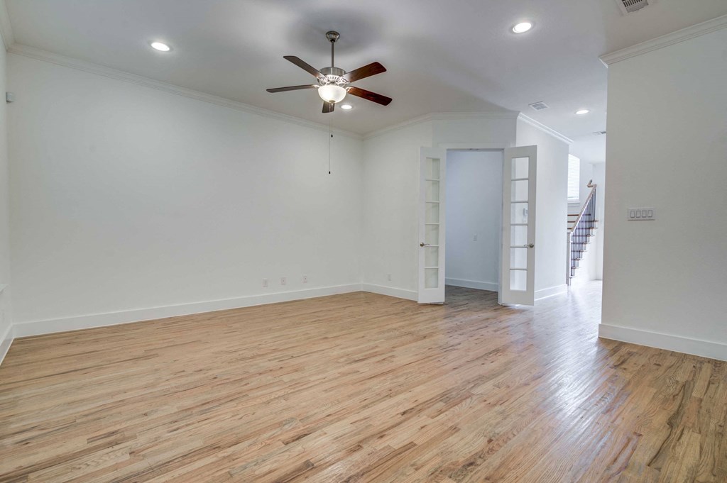 an empty living room with wood floors and a ceiling fan
