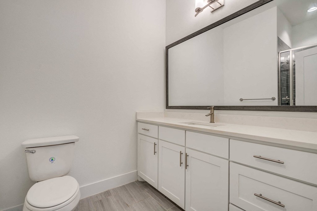 a white bathroom with a large mirror and a toilet