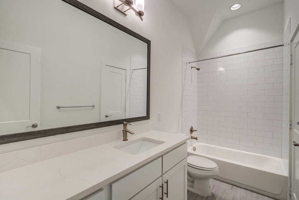 a white bathroom with a large mirror and a toilet and a sink