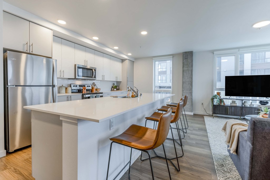 a kitchen with a white counter top and bar stools at Riverfront Everett, Everett