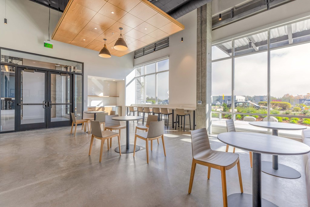 a common area with tables and chairs and a view of the city at Riverfront Everett, Washington, 98101