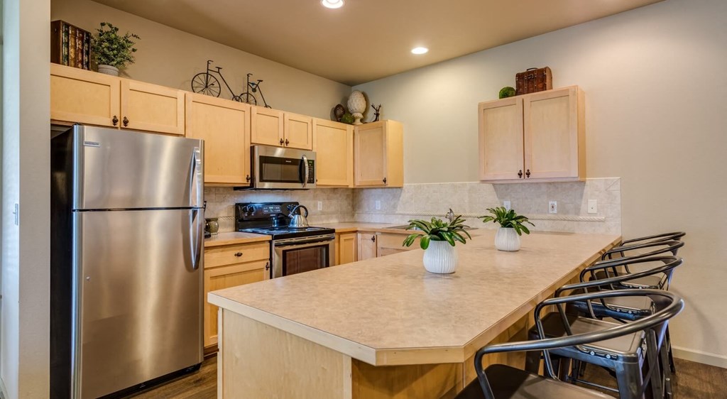Coeur d'Alene, ID, Apartments For Rent - Rockwood Lodge - Spacious Kitchens With Abundant Cabinets, Wood-Style Flooring, Stainless Steel Appliances, And Breakfast Bar With Seating.