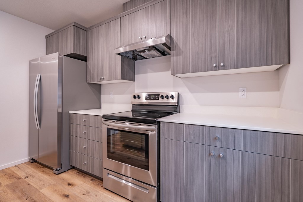 a kitchen with gray cabinets and stainless steel appliances