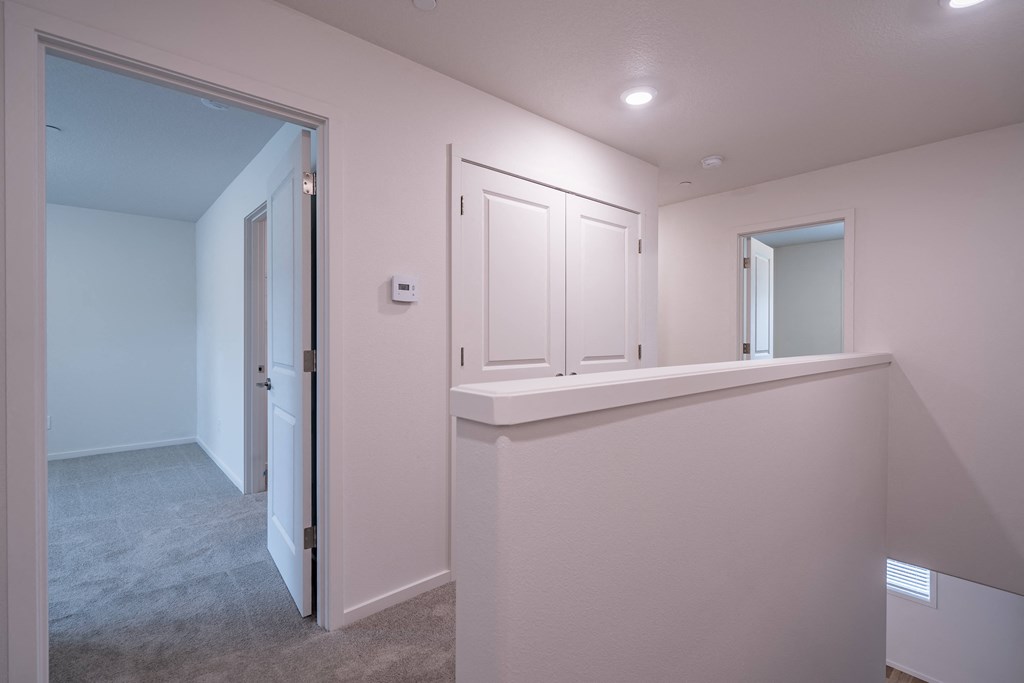 a hallway in a home with a white wall and grey carpet