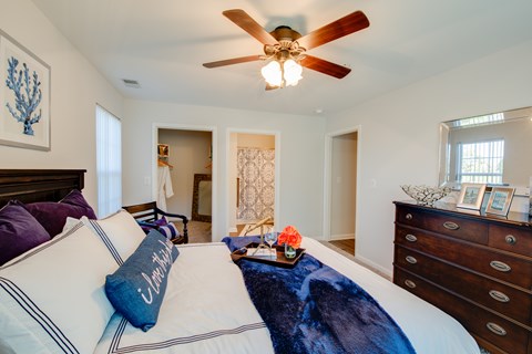 A bedroom with a bed, dresser, and ceiling fan.