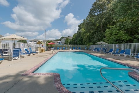 A large outdoor swimming pool with blue water and a red and white checkered border.