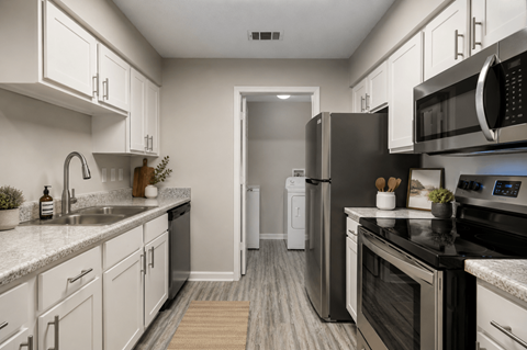 A modern kitchen with white cabinets and stainless steel appliances.
