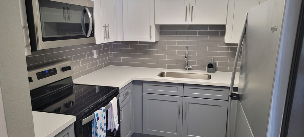 a small kitchen with white cabinets and black counter tops