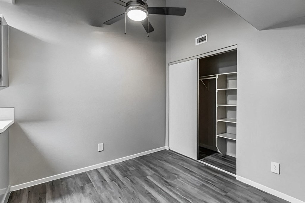 an empty living room with a closet and a ceiling fan