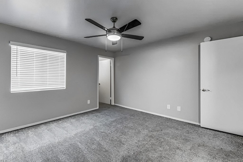 an empty living room with a ceiling fan and a door to a closet