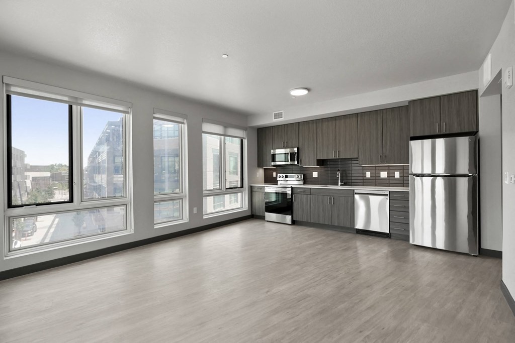 an empty room with a large window and a stainless steel refrigerator