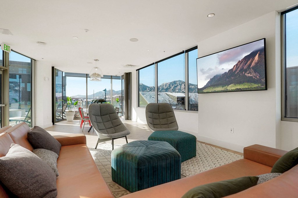 a living room with orange couches and green chairs with a large tv on the wall