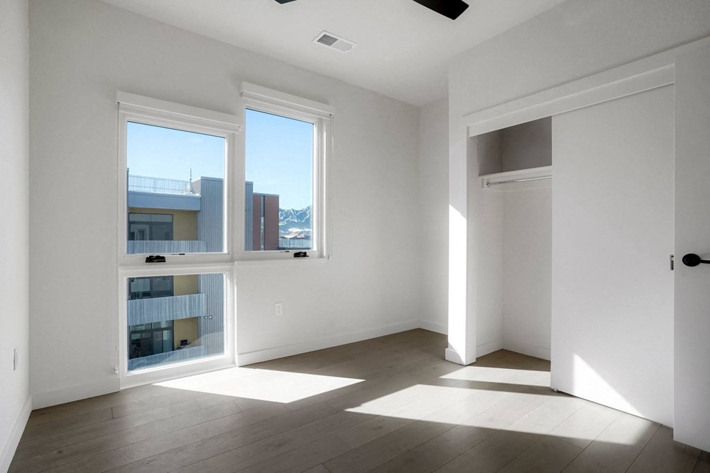 a bedroom with three large windows and a door that leads to a balcony