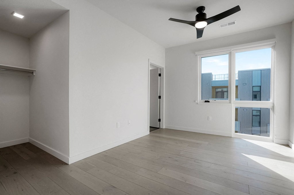a bedroom with a large window and a ceiling fan