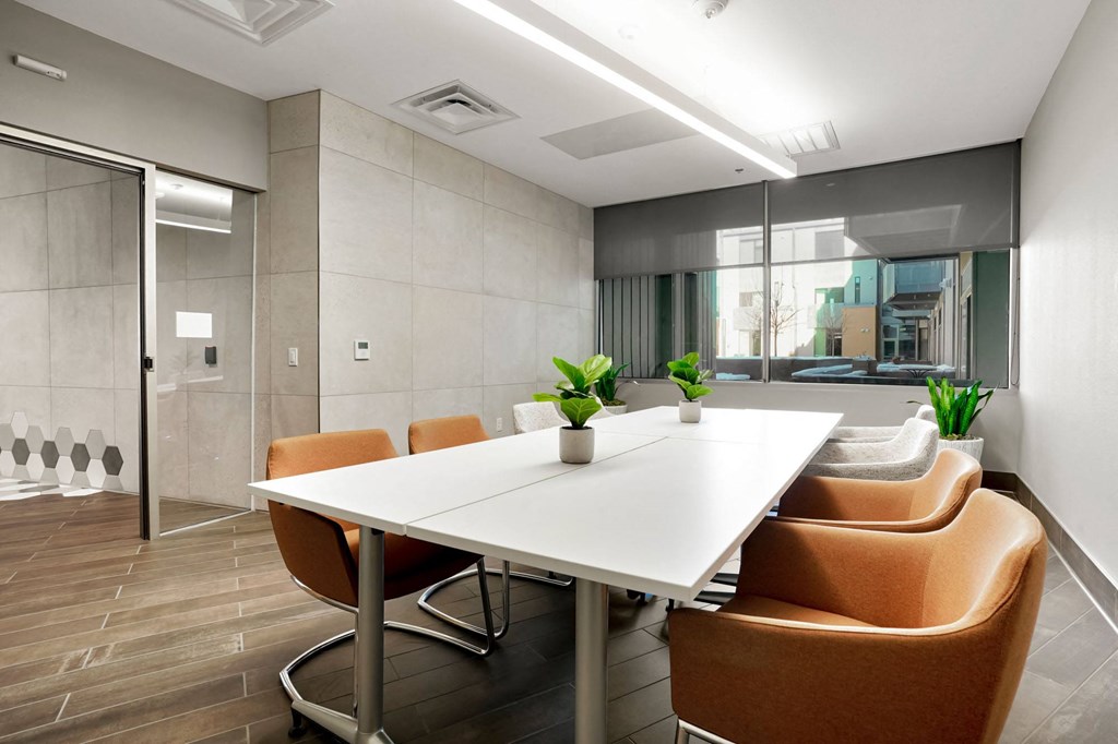 a meeting room with a white table and orange chairs