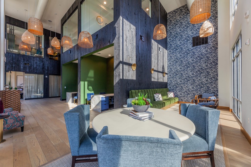 a communal area with a round table with blue chairs and a green couch in the background