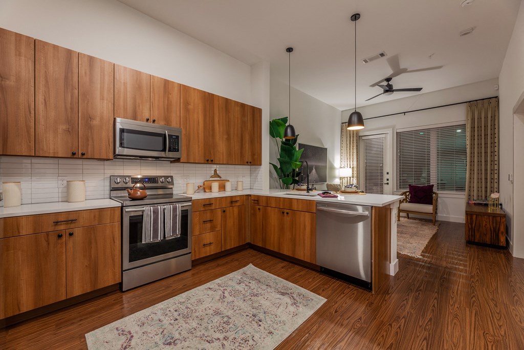 2-Bedroom Apartments in Old East Dallas, TX - 4600 Ross - Kitchen with Hardwood-Style Flooring, Wood Cabinets, White Countertops, White Tile Backsplash, and Stainless Steel Appliances