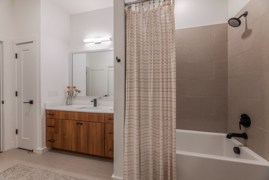 One-Bedroom Apartments in Old East Dallas, TX - 4600 Ross - Bathroom with Wood Cabinets, White Counters, a Shower with a Tub, and Tile Flooring