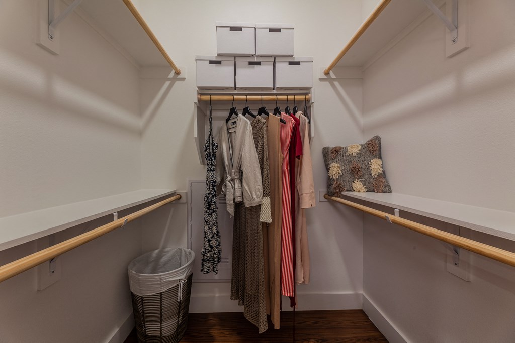 a walk in closet with white walls and wooden shelves