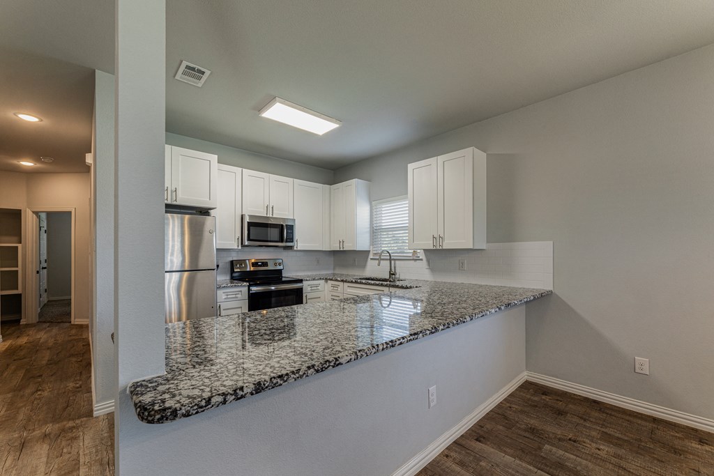a kitchen with granite countertops and white cabinets