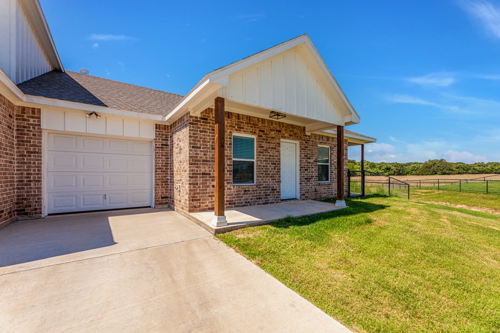a home with a white garage door and a grassy field in the background