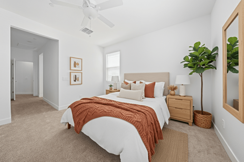A bedroom with a bed, nightstand, and a plant.