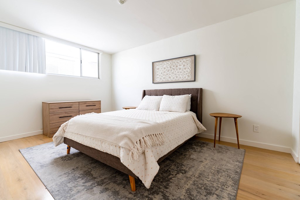 One, Two, and Three-BR Apartments in Santa Monica, CA - San Vicente Tower - Bedroom with Large Window, Hardwood Flooring, Bed, Dresser, and Large Window