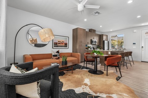 A living room with a brown leather couch and a black and white cowhide rug.