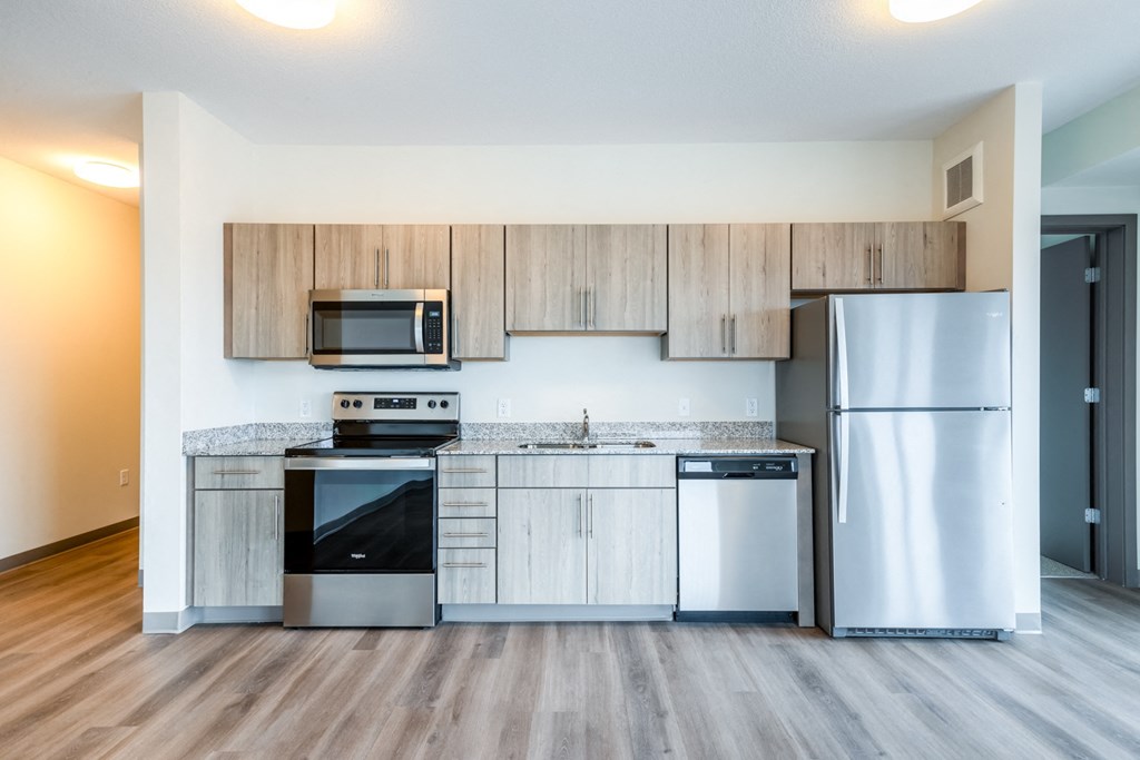an empty kitchen with stainless steel appliances and wooden cabinets