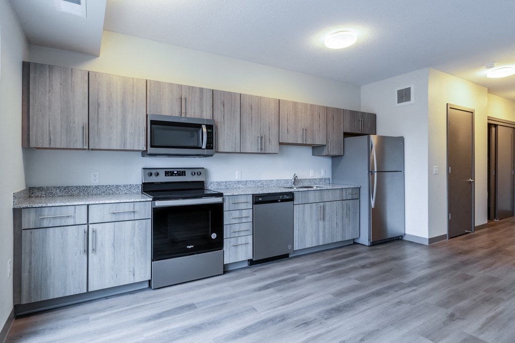 an empty kitchen with stainless steel appliances and wooden cabinets