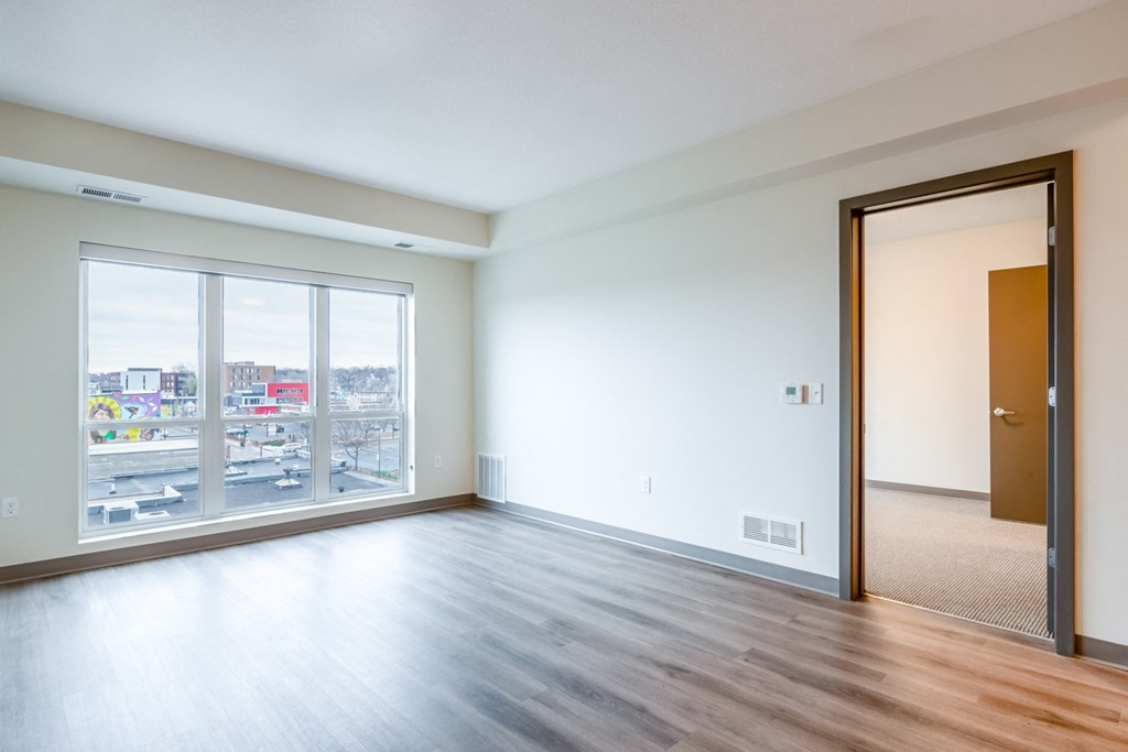 an empty living room with wood flooring and a large window