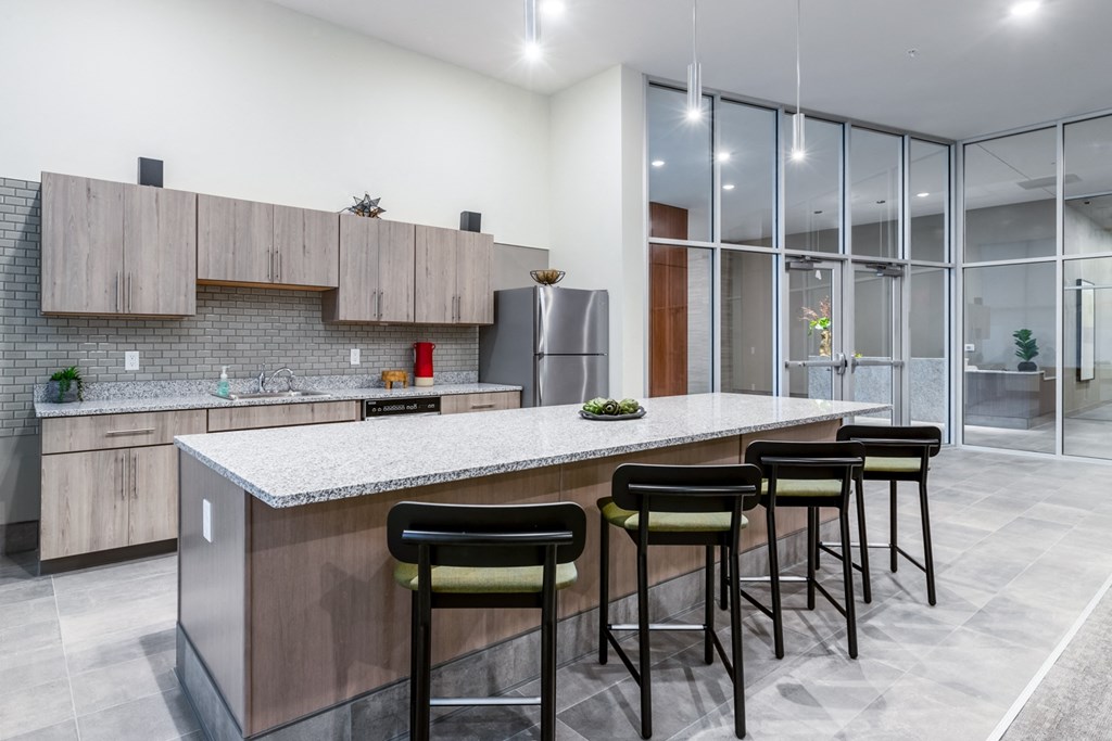 a kitchen with a large island with bar stools and a stainless steel refrigerator
