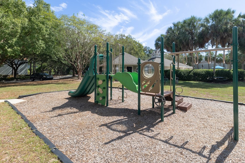 A playground with a green slide and a yellow and green play structure.