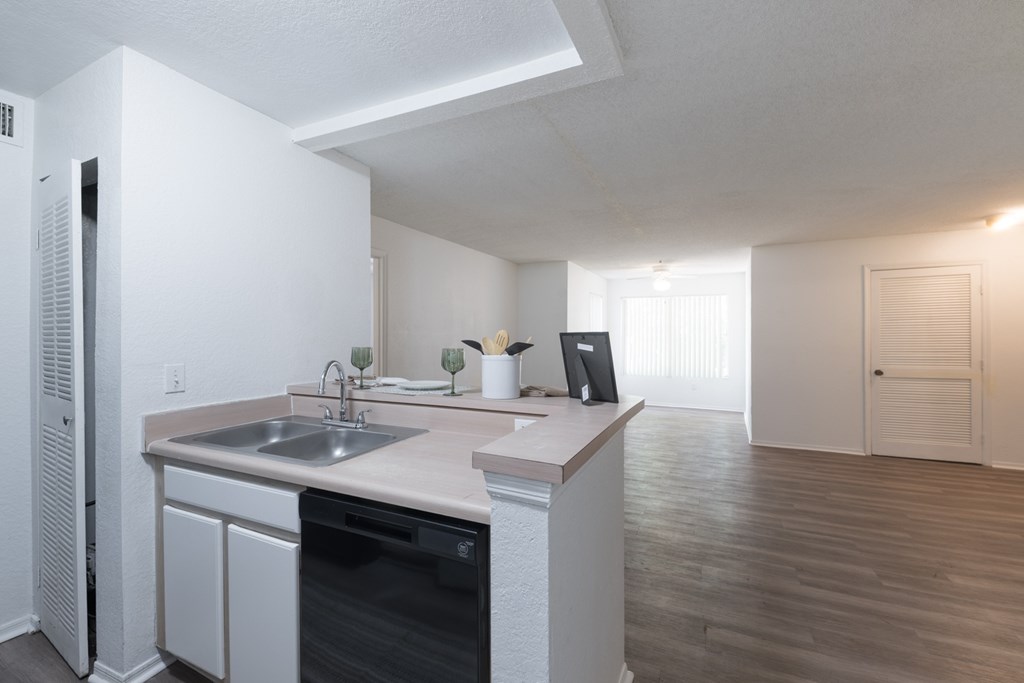 A kitchen with a sink, dishwasher, and a refrigerator.