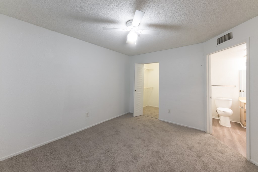 A room with a carpeted floor and a ceiling fan.