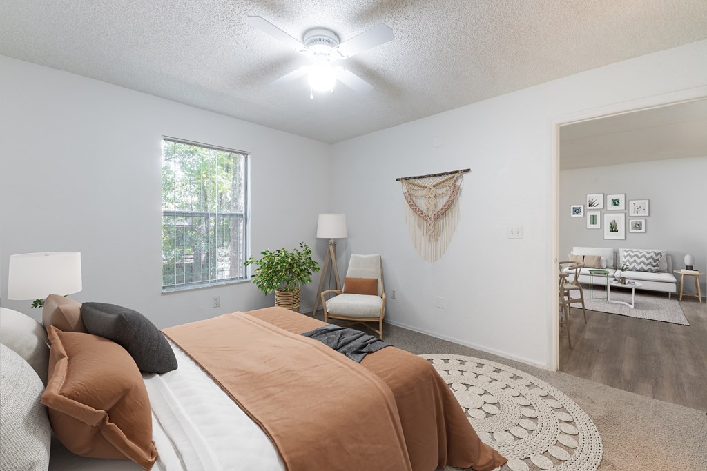 A bedroom with a bed, a chair, a couch, and a wall hanging.
