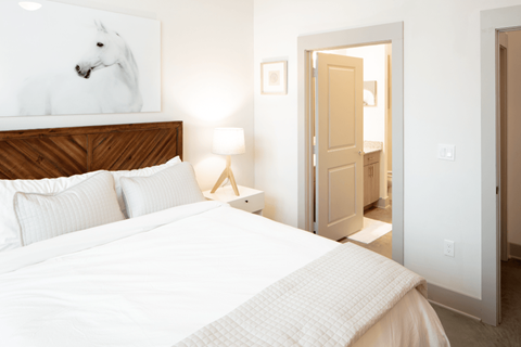 A bedroom with a large bed and a painting of a horse on the wall.