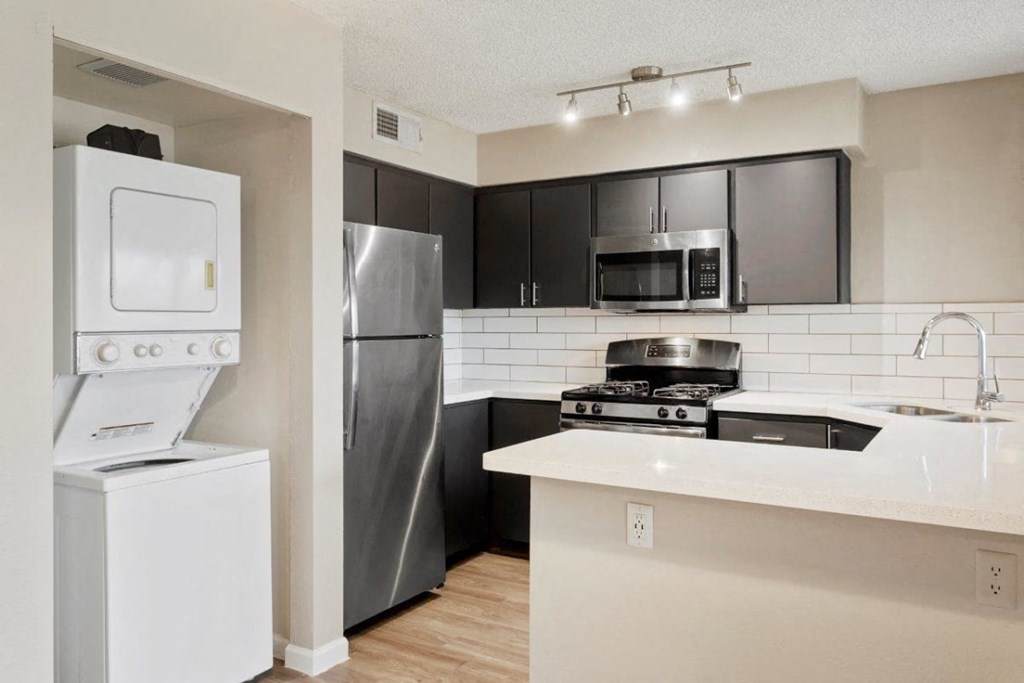 Kitchen with stainless steel appliances and washer and dryer next to it at Sentry Tempe apartments in Tempe near Mesa, Arizona