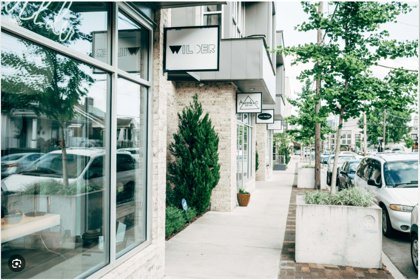 Shops and boutiques line a sidewalk in a city neighborhood.