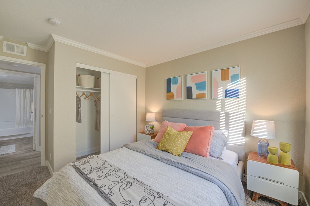 One-Bedroom Apartments in Moreno Valley, CA - Ardella on Chagall - Bedroom with Carpeted Flooring, Bed, Nightstands with Lamps, Cream-Colored Walls, and Large Closet.