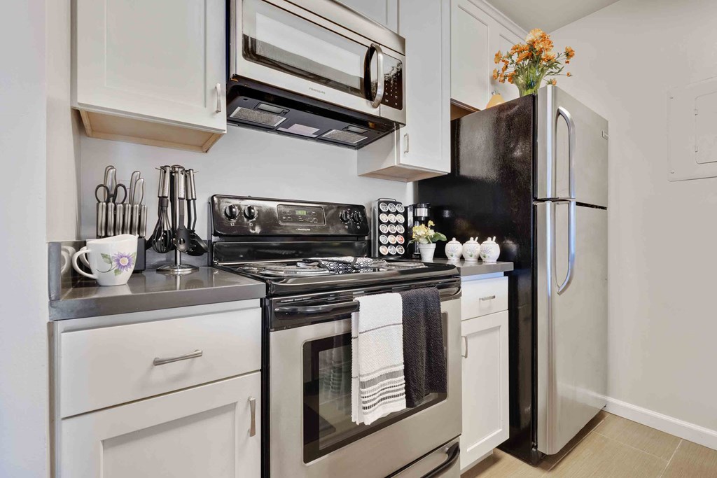 One-Bedroom Apartments in Daly City, CA - Serra Commons - Kitchen with Stainless-Steel Appliances, White Cabinets, and Tiled Floor.