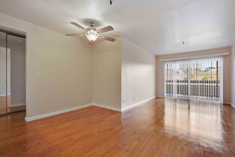 an empty living room with a ceiling fan and a window