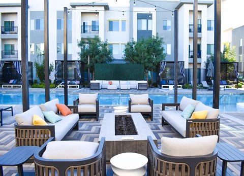A poolside seating area with a variety of cushions and chairs.