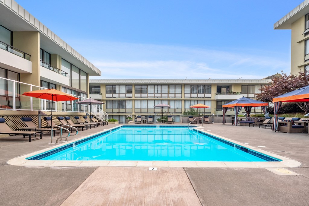 a swimming pool with chairs and umbrellas in front of a building