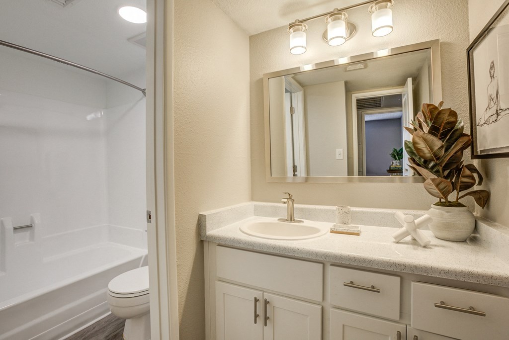 Glendale, AZ Apartments for Rent - Ardella on 67th - Bathroom with Bath Tub, Vanity Mirror, and White Cabinets.